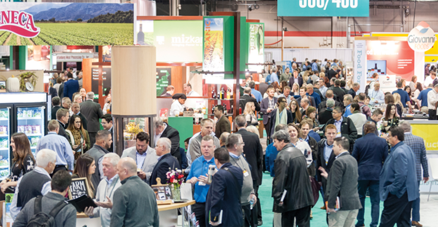 Large groups of suited individuals walking the trade show floor at the PLMA