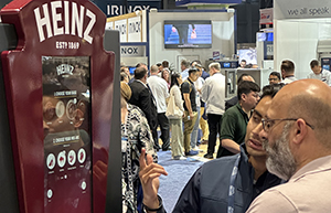 Red machine with a touchscreen interface with two people looking at it at the National Restaurant Association Show