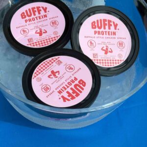 pink lids on hummus containers in a bucket of ice water.