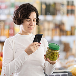 Woman get acquainted with food, scan QR code, take reading olives label using phone camera