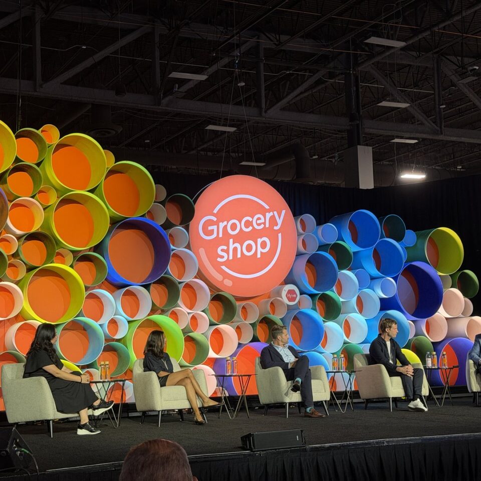 groceryshop 2026 capsule stage featured square Five panelists seated on the Groceryshop Capsule Stage in front of a wall of colored circles and a large orange Groceryshop logo.
